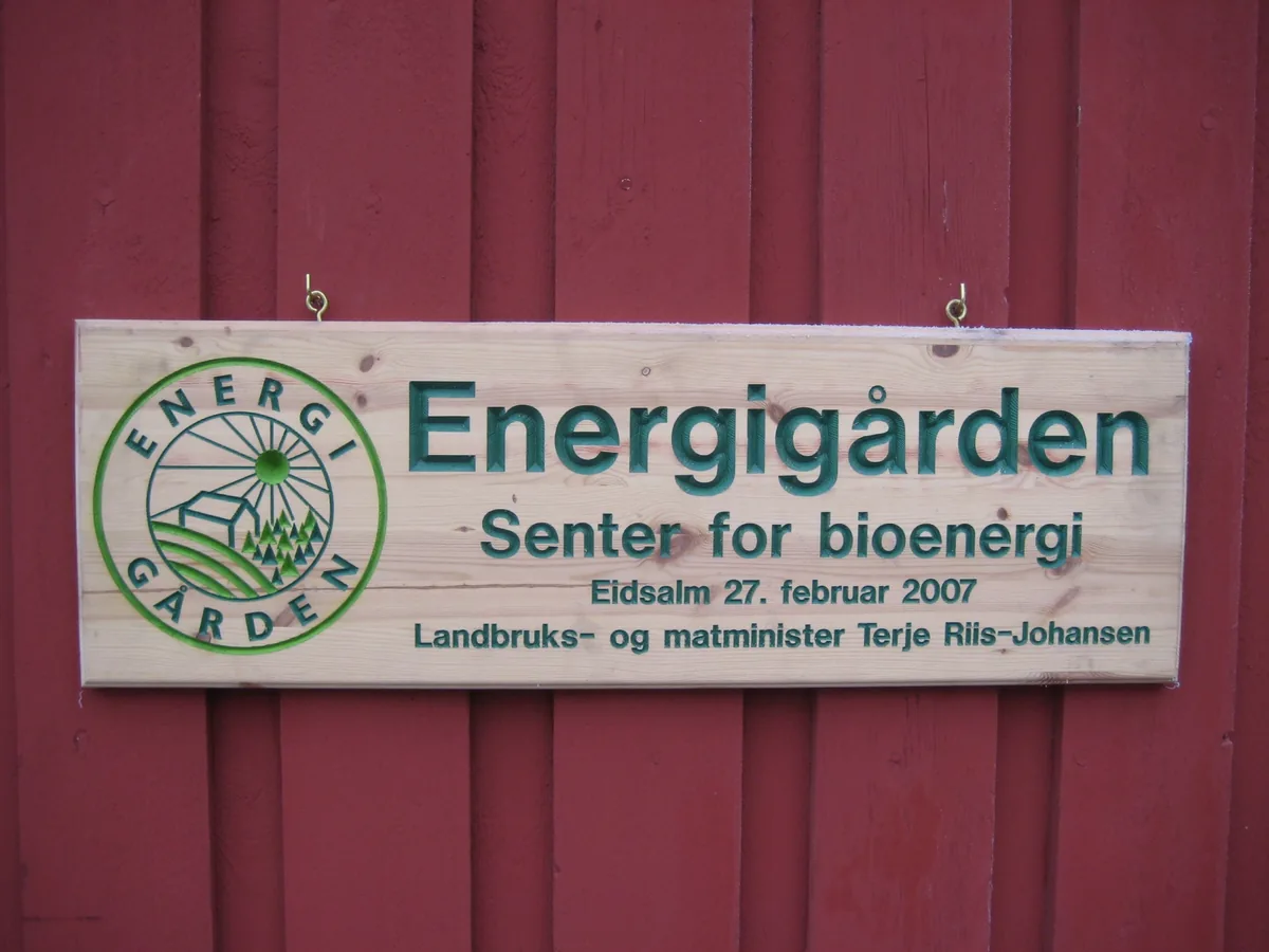 Skiltet «Energigården, senter for bioenergi» på veggen av den røde låven på Eidsalm.